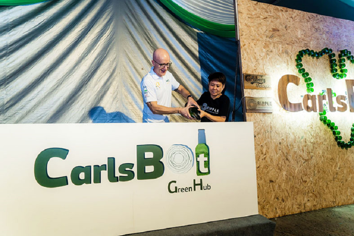 Carlsberg Malaysia’s Managing Director Stefano Clini and Ripple Sabah’s Chairperson  Tressie Yap pouring pulverised Carlsberg glass bottles into the lightbox signage to signify  the launch of Project CarlsBot.